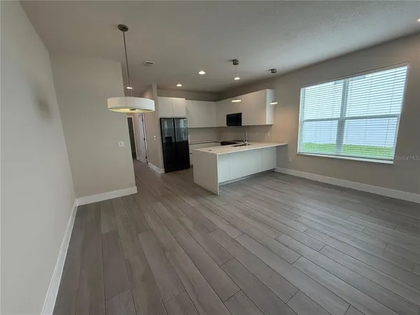 a large kitchen with kitchen island a sink dishwasher a refrigerator and wooden floor