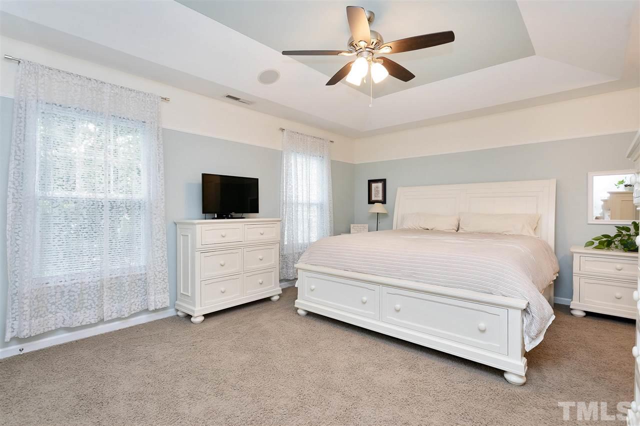 2408 Memory Ridge Drive Raleigh, NC 27606 - Photo 19 of 30 a spacious bedroom with a bed a flat screen tv and a chandelier