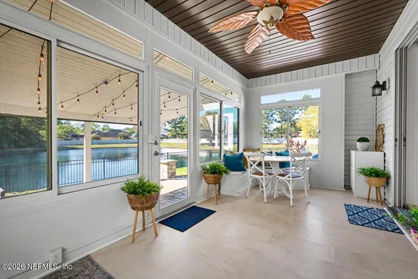 a living room with patio furniture and floor to ceiling windows