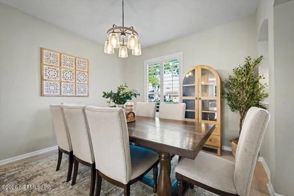 a large white kitchen with stainless steel appliances granite countertop a sink a stove a refrigerator a dining table and chairs with wooden floor