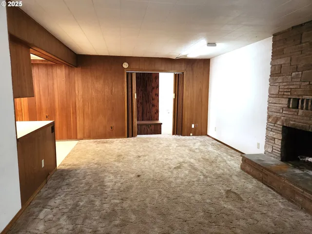 an empty room with windows and fireplace