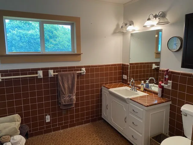 a bathroom with a double vanity sink a toilet a mirror and a window