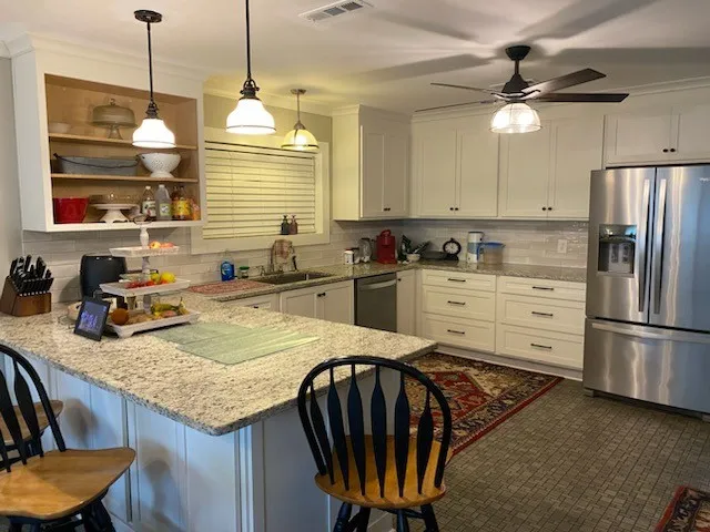 a kitchen with stainless steel appliances granite countertop a sink a stove a refrigerator a dining table and chairs