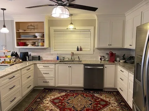 a kitchen with granite countertop white cabinets stainless steel appliances a sink and a window