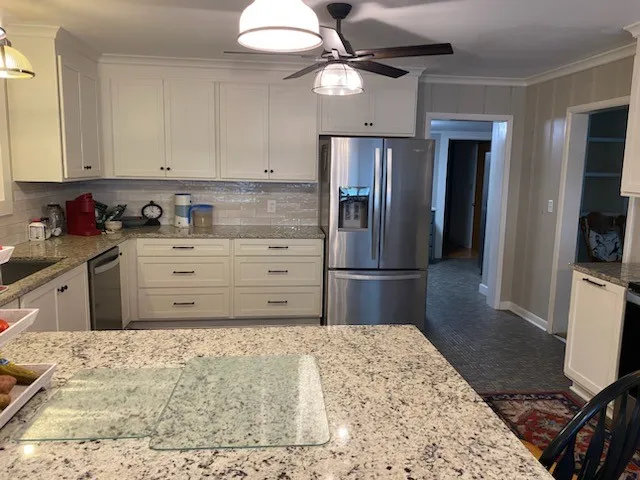 a kitchen with stainless steel appliances kitchen island granite countertop a refrigerator and a stove top oven