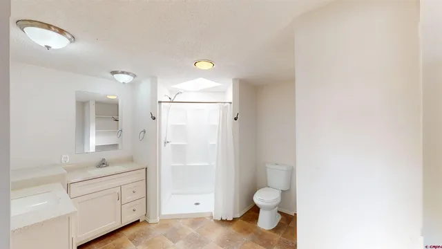 a bathroom with a granite countertop toilet sink and mirror