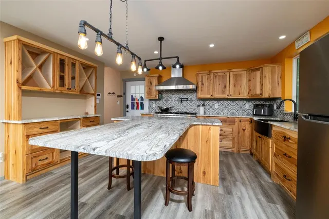 a kitchen with stainless steel appliances granite countertop a stove top oven a sink a dining table and chairs with wooden floor