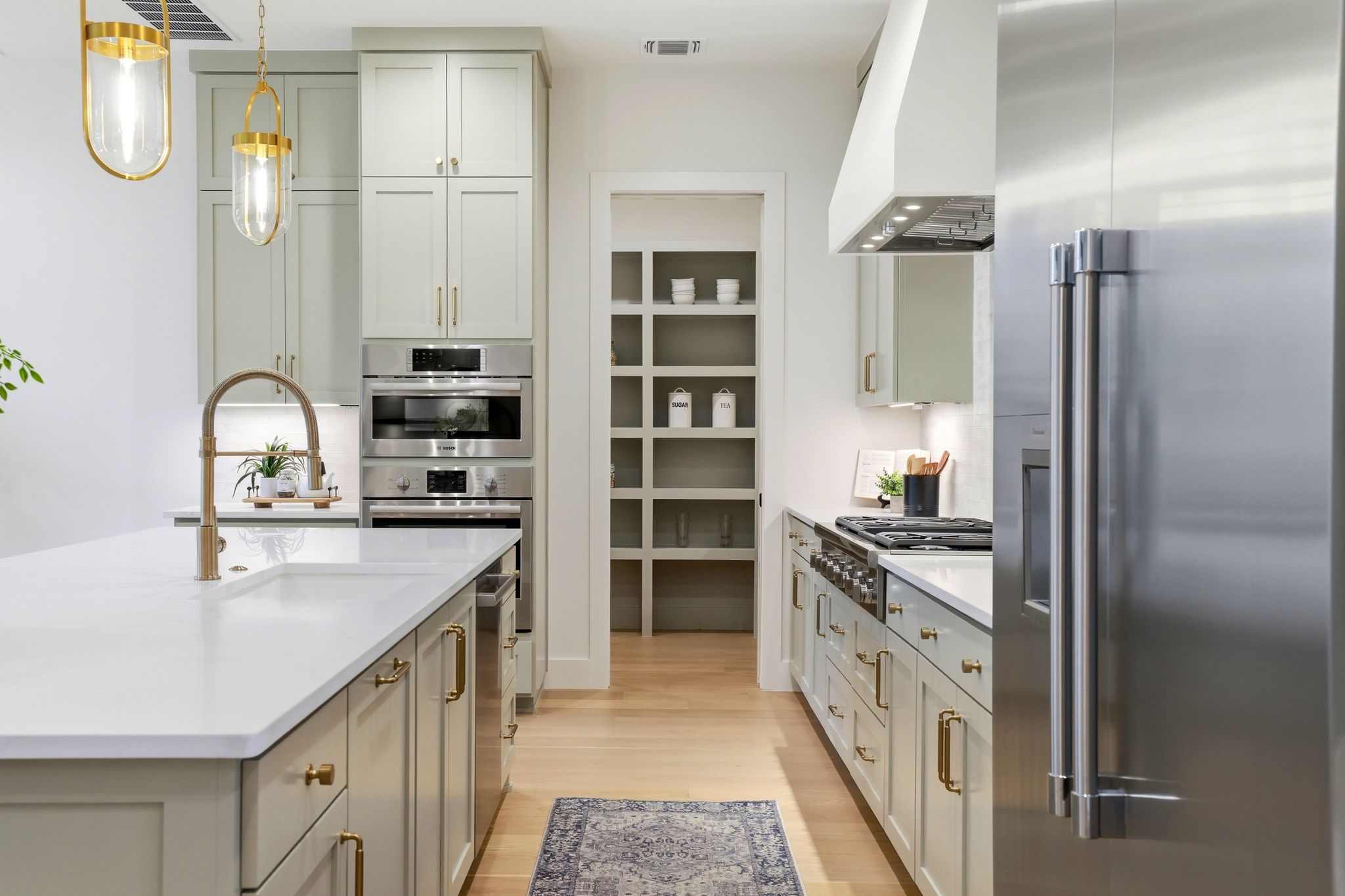 3005 Silverleaf Drive Austin, TX 78757 - Photo 9 of 38 Dual tone kitchen with stainless steel appliances, pendant lighting, light wood finished floors, light stone countertops, and a center island with sink