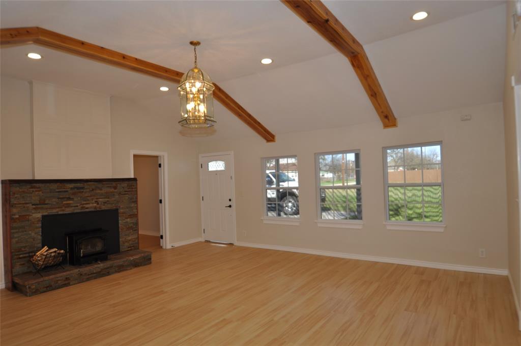 209 West 5th Street Tolar, TX 76476 - Photo 4 of 11 a view of an empty room with wooden floor fireplace and a window
