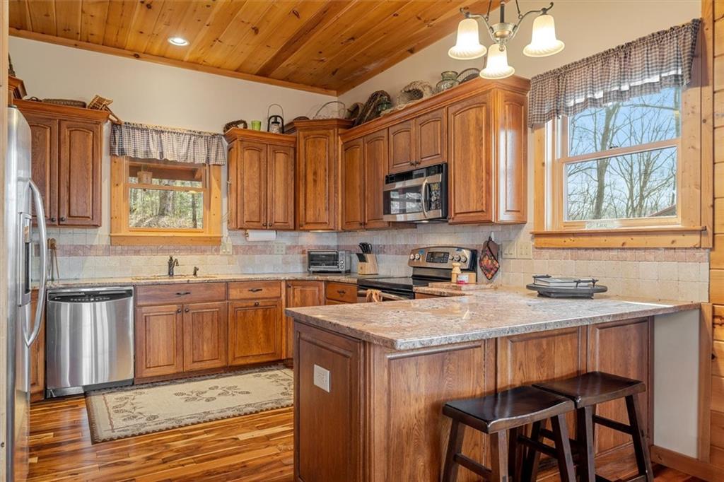 881 Fox Mountain Road Cherry Log, GA 30522 - Photo 25 of 65 a kitchen with stainless steel appliances granite countertop a stove a sink dishwasher and microwave with wooden cabinets