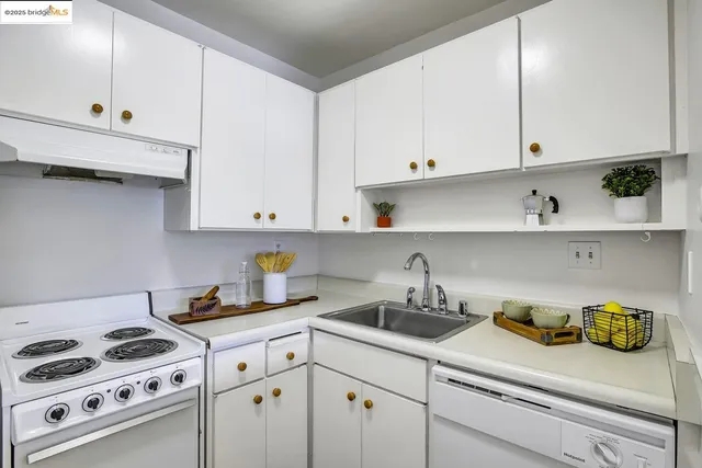 a kitchen with stainless steel appliances a white stove top oven and white cabinets