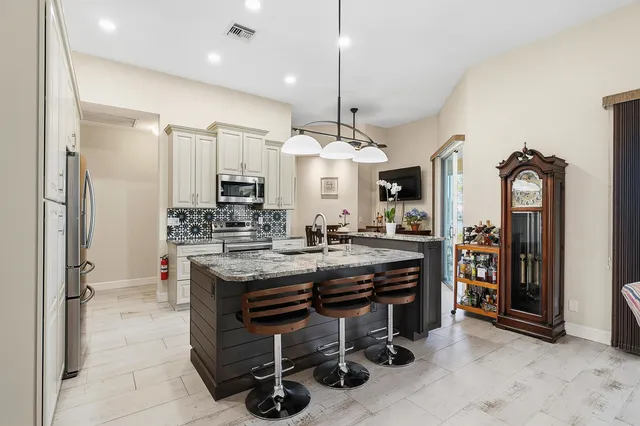 a kitchen with stainless steel appliances a table chairs refrigerator and sink