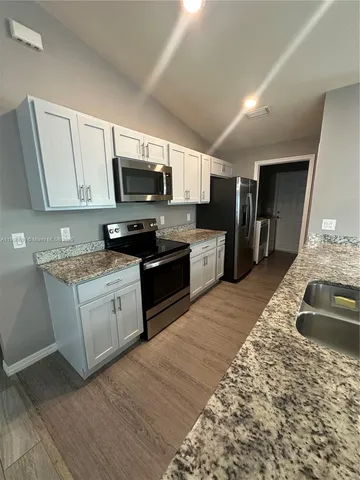 a kitchen with stainless steel appliances granite countertop a sink dishwasher stove top oven and refrigerator