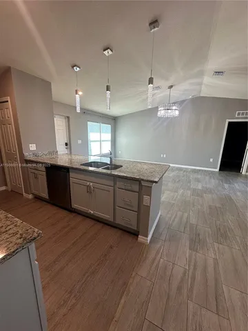 a large kitchen with stainless steel appliances a large counter top a sink a refrigerator and a stove