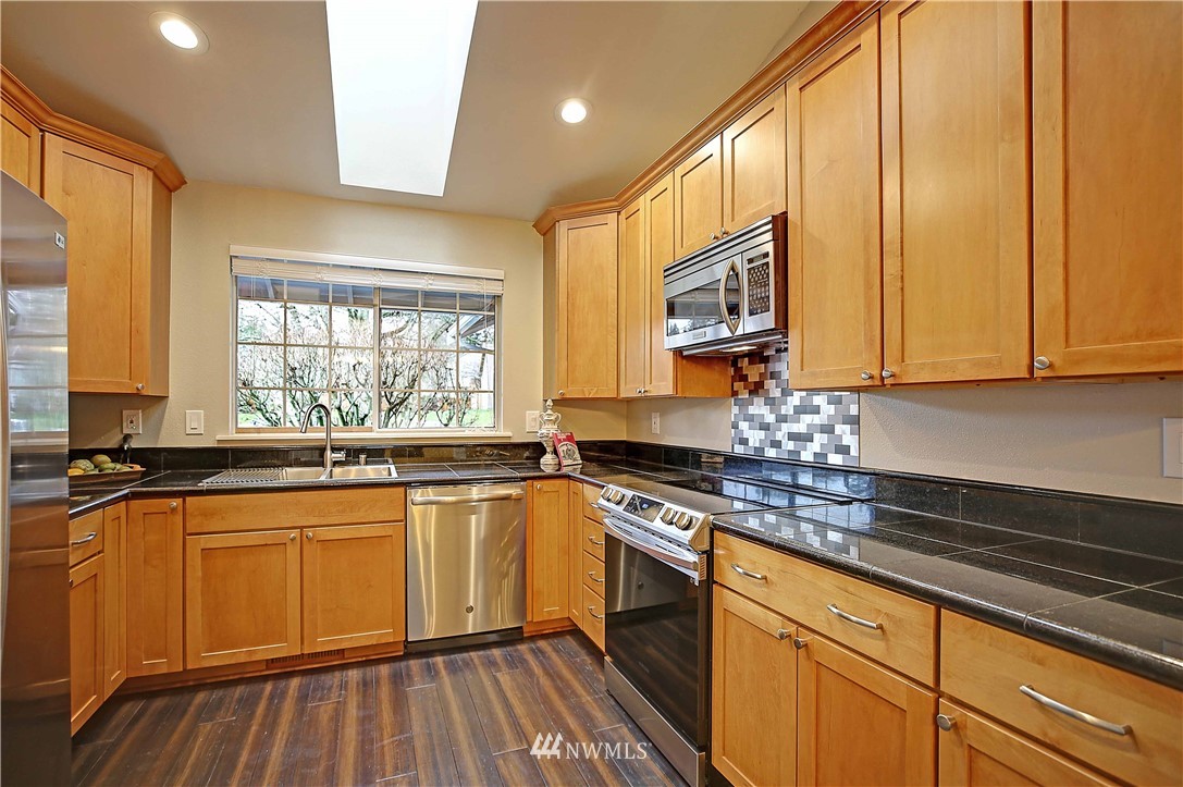 609 213th Street Southwest Bothell, WA 98021 - Photo 8 of 31 a kitchen with stainless steel appliances granite countertop wooden cabinets a sink and dishwasher
