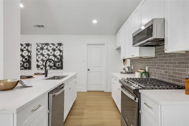 a kitchen with stainless steel appliances a sink stove and cabinets