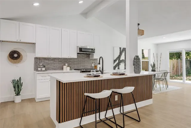 a kitchen with stainless steel appliances granite countertop a table chairs sink and cabinets