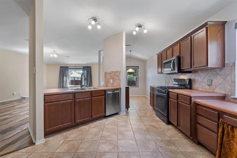 a large kitchen with stainless steel appliances granite countertop a stove a sink and a microwave