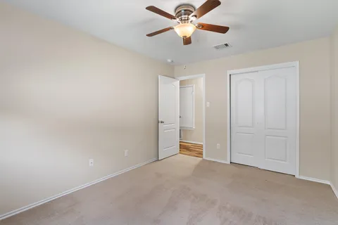 an empty room with closet and a chandelier fan