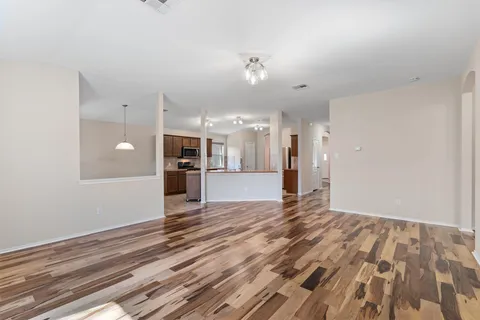 a view of an empty room with kitchen and a window