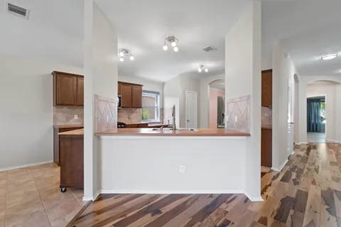 a view of a kitchen with kitchen island a sink stainless steel appliances and cabinets