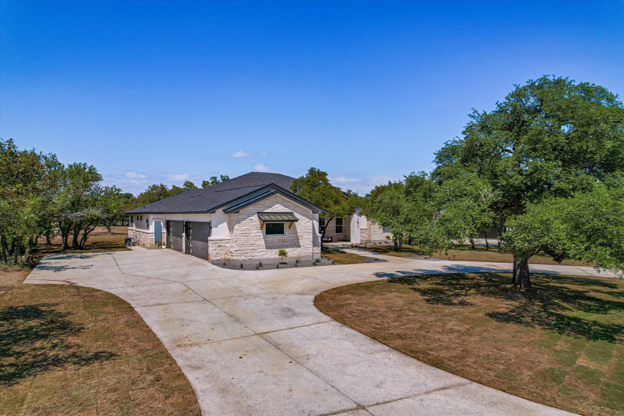 410 Shady Tree Drive Georgetown, TX 78633 - Photo 31 of 40 View of front of property with stone siding, curved driveway, a garage, and a front lawn