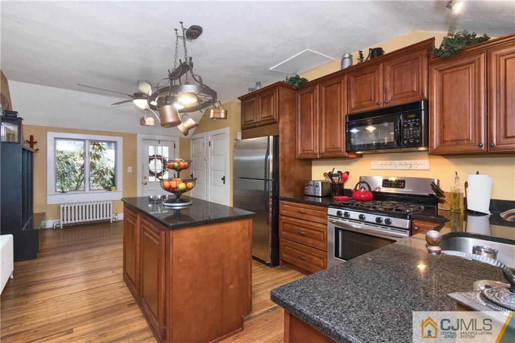 19 Reids Hill Road Morganville, NJ 07751 - Photo 10 of 24 a kitchen with granite countertop a stove top oven a sink dishwasher and a refrigerator with wooden floor