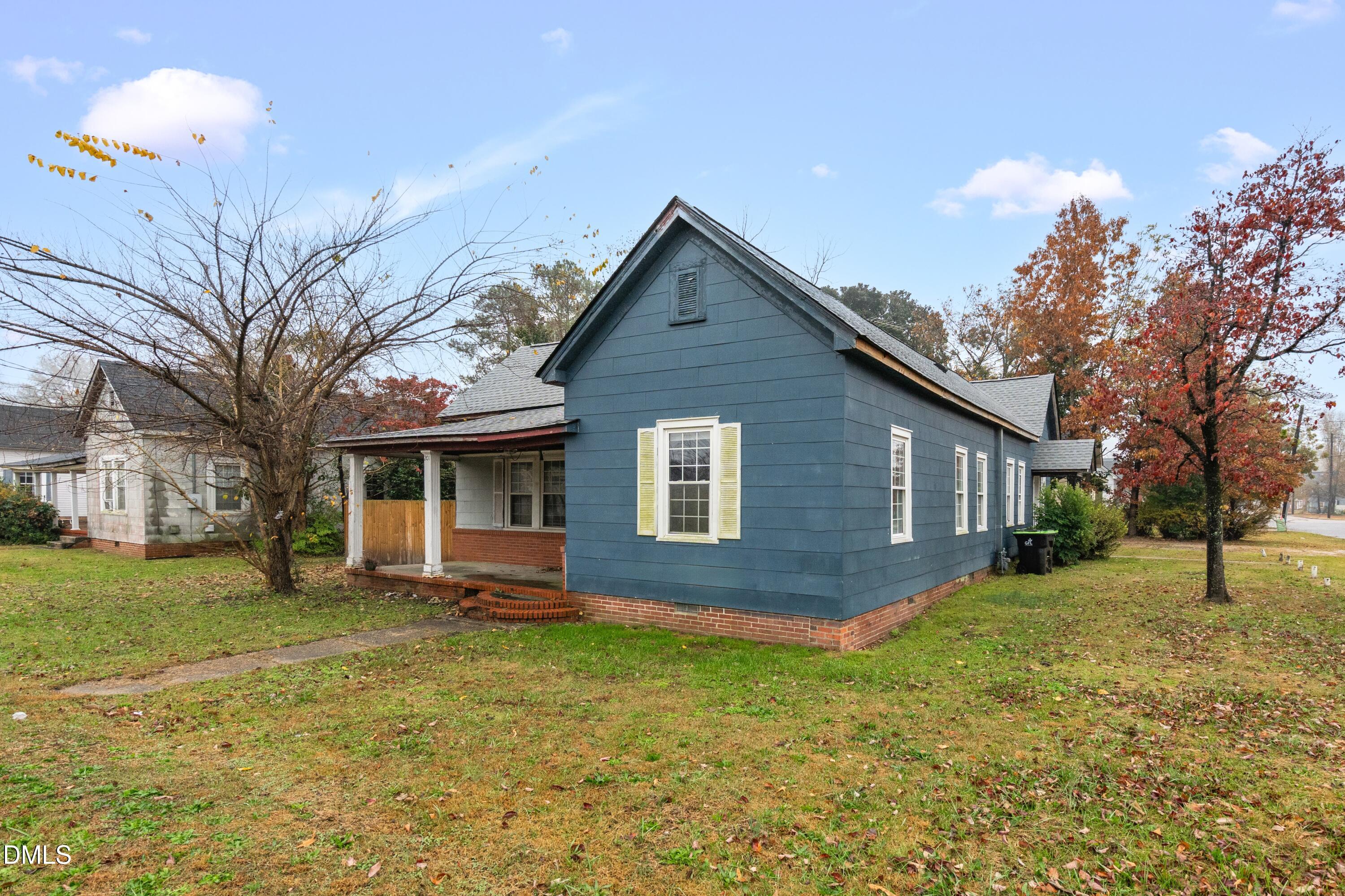 a brick house next to a yard with a large tree