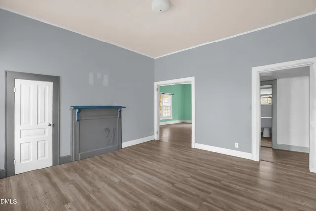 a view of an empty room with wooden floor and closet