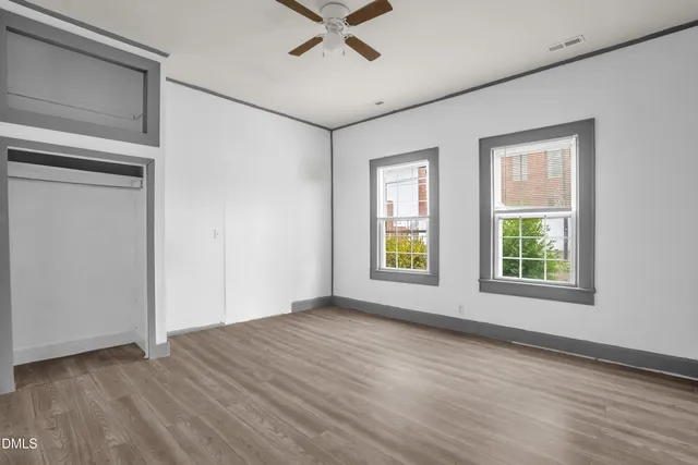 a view of an empty room with a window and wooden floor
