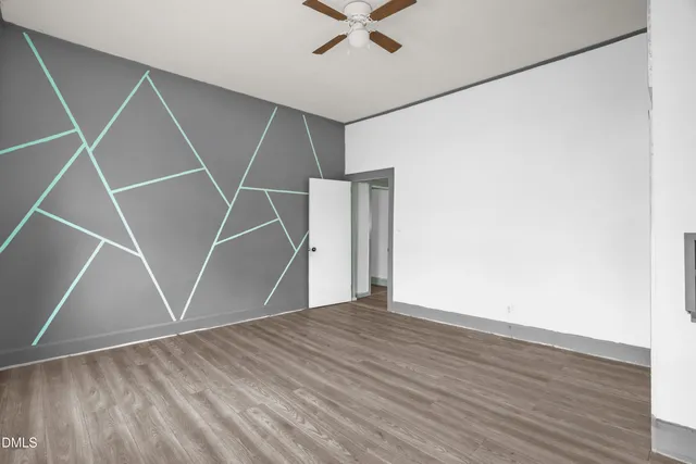 an empty room with wooden floor and a ceiling fan
