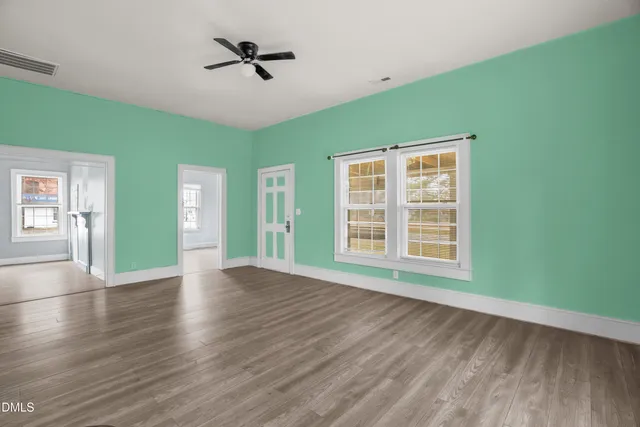 a view of an empty room with a window and wooden floor