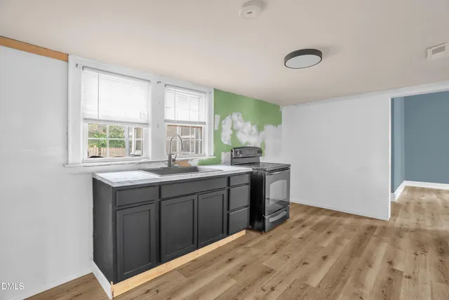 a kitchen with granite countertop a sink cabinets and wooden floor