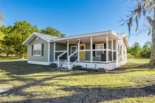 a front view of a house with yard and trees in the background