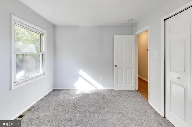 a view of an empty room with window and bathroom