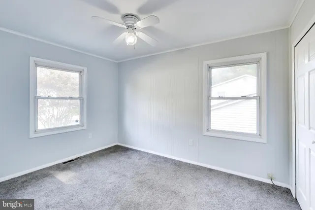 an empty room with a window and a ceiling fan