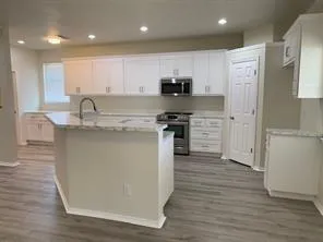 a kitchen with stainless steel appliances granite countertop a stove top oven a sink and a refrigerator