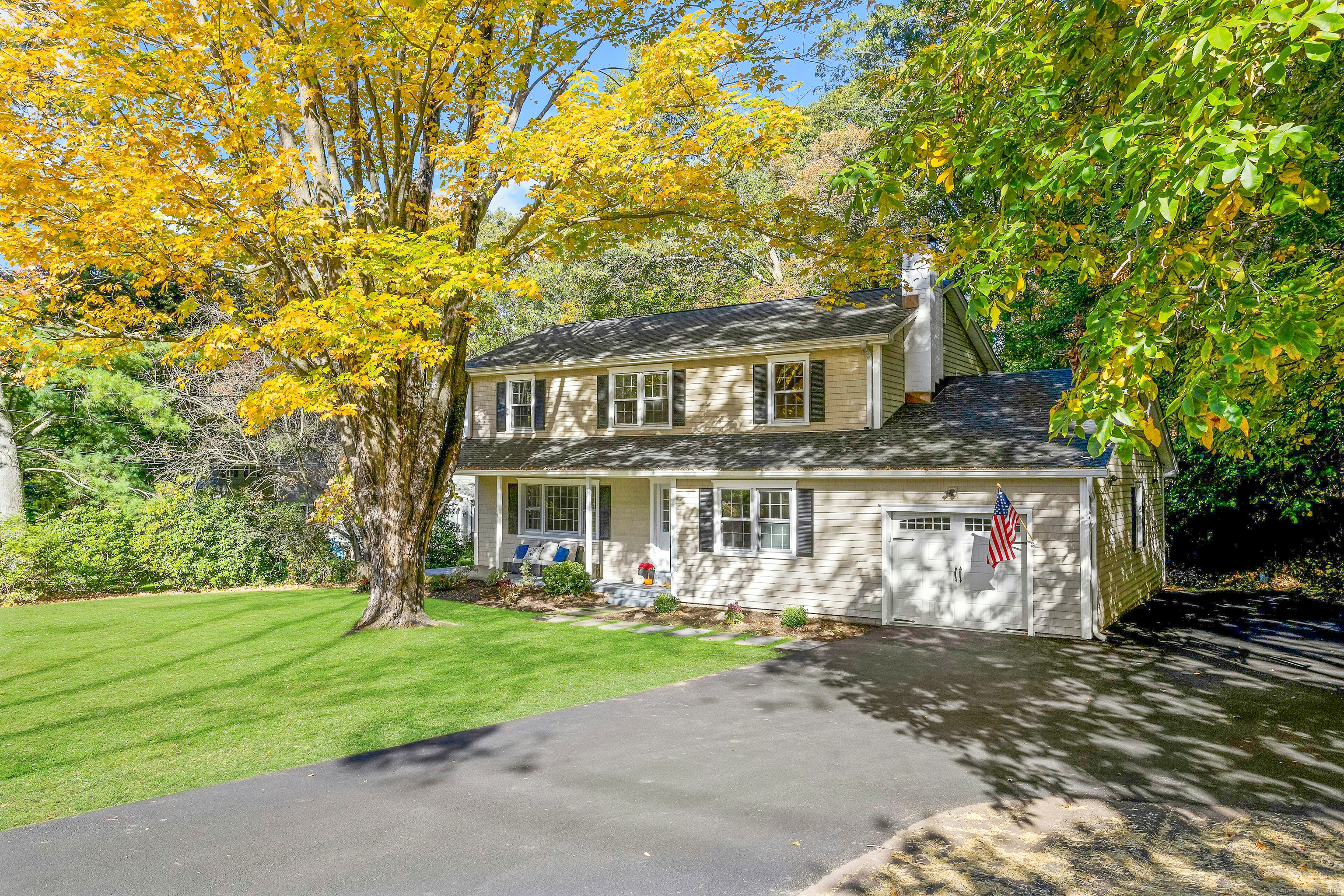 a front view of a house with garden and trees