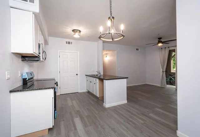 a kitchen with stainless steel appliances granite countertop a sink a stove and a wooden floors