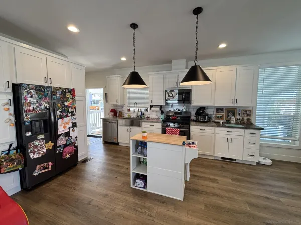 a kitchen view with stainless steel appliances kitchen island granite countertop a stove a sink a refrigerator and cabinets
