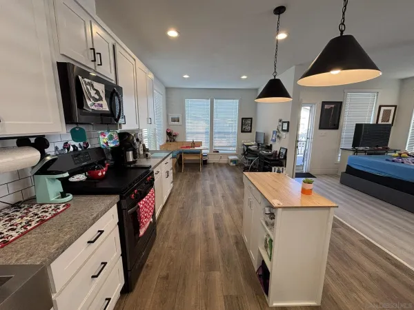 a kitchen with stainless steel appliances granite countertop a stove top oven a sink dishwasher a dining table and chairs with wooden floor