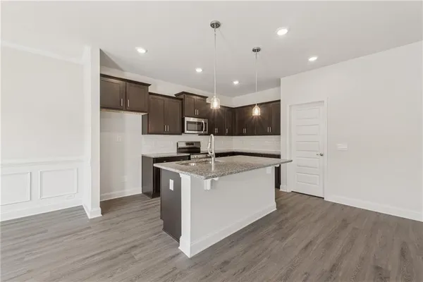 a large kitchen with stainless steel appliances granite countertop a white stove top oven and white cabinets