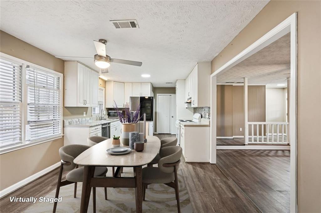 5151 Lilburn Stone Mountain Road Lilburn, GA 30047 - Photo 15 of 58 a kitchen with a dining table chairs and refrigerator
