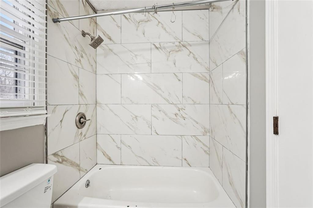 5151 Lilburn Stone Mountain Road Lilburn, GA 30047 - Photo 29 of 58 a bathroom with a bathtub and a shower