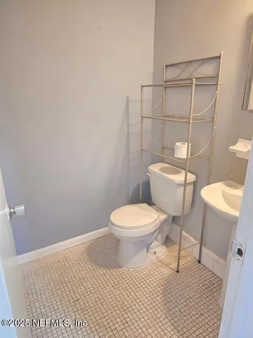 a white toilet sitting next to a bathroom sink and a mirror