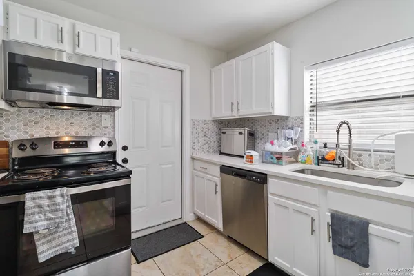 a kitchen with stainless steel appliances a stove a sink dishwasher a refrigerator and a microwave
