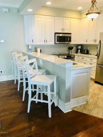 a kitchen with kitchen island granite countertop a stove top oven a sink a counter space and cabinets