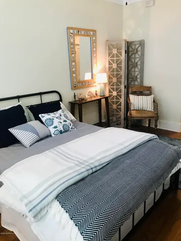 a bedroom with a bed a dresser and next to a window