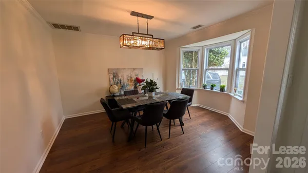 a dining room with wooden floor a chandelier a wooden table and chairs