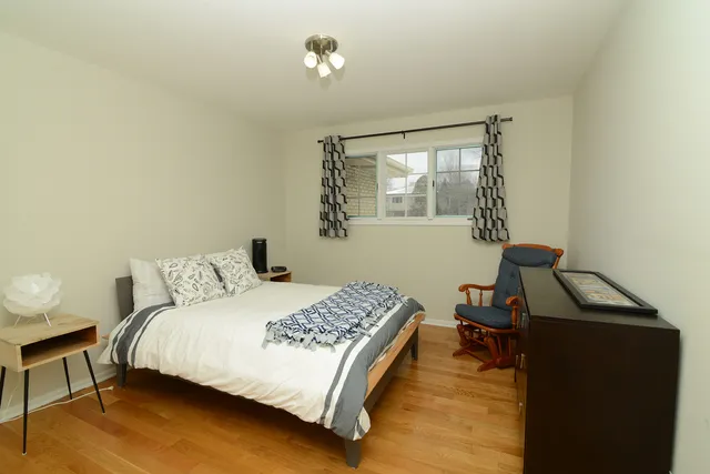 a bedroom with a bed and a potted plant on the dresser